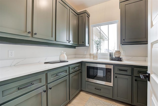 kitchen with built in microwave, light stone countertops, and light hardwood / wood-style floors