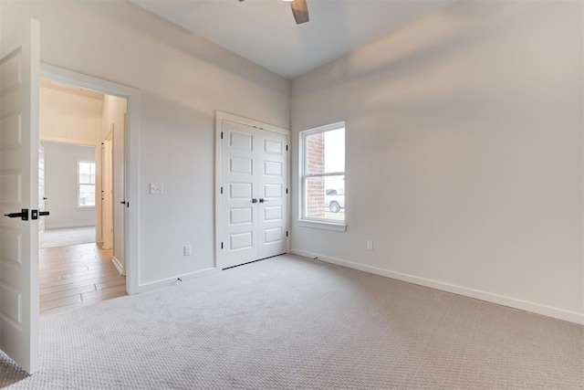 unfurnished bedroom with ceiling fan, light colored carpet, and a closet