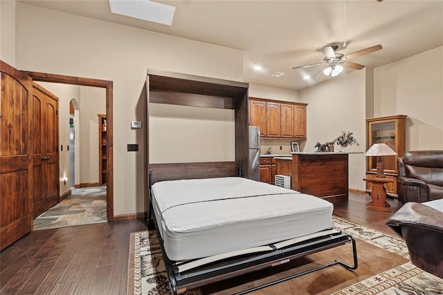 bedroom with dark hardwood / wood-style flooring, stainless steel refrigerator, and ceiling fan