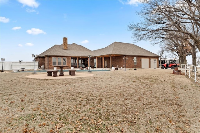 rear view of house featuring a garage, a yard, and a patio