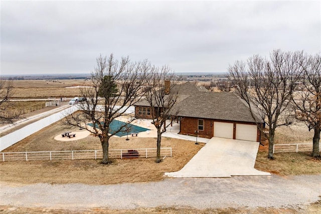 view of front of home featuring a garage and a rural view