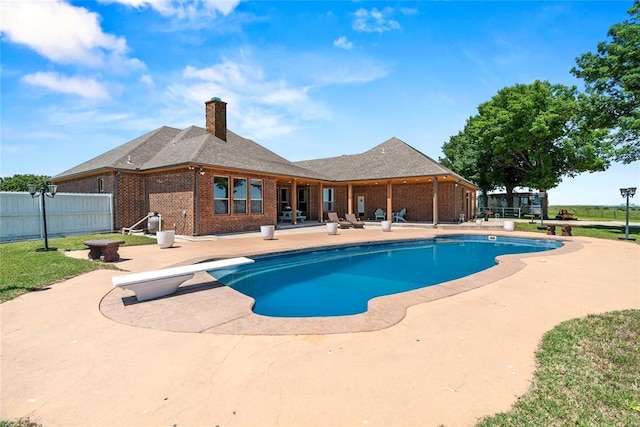 view of swimming pool with a patio, fence, and a diving board