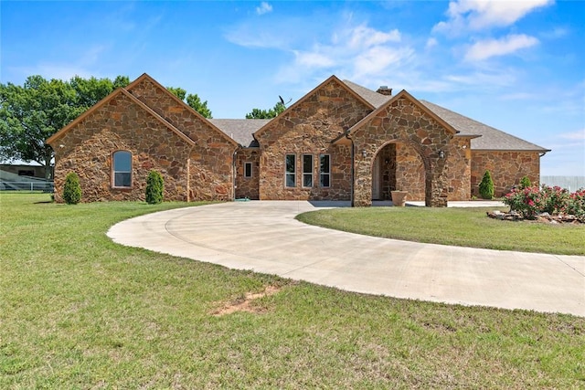 view of front facade with stone siding, a front lawn, and a chimney