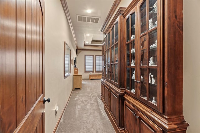 corridor featuring ornamental molding, light carpet, baseboards, a raised ceiling, and recessed lighting