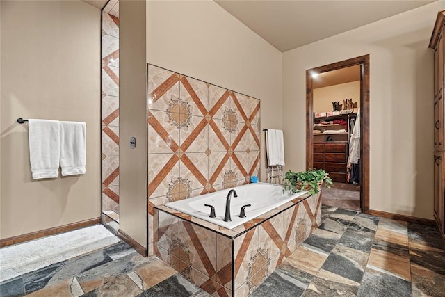 bathroom with a walk in closet, baseboards, and a garden tub