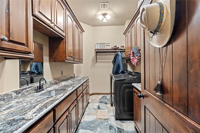 washroom with washer and dryer, cabinet space, stone tile flooring, and baseboards