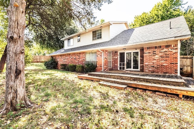 rear view of house featuring a lawn and a deck