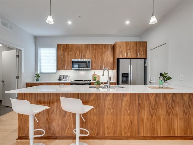 kitchen featuring stainless steel appliances, sink, decorative backsplash, and decorative light fixtures