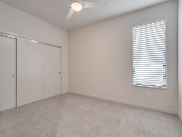 unfurnished bedroom featuring light carpet, a closet, and ceiling fan