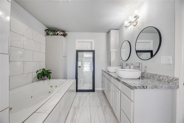 bathroom featuring a relaxing tiled tub and vanity