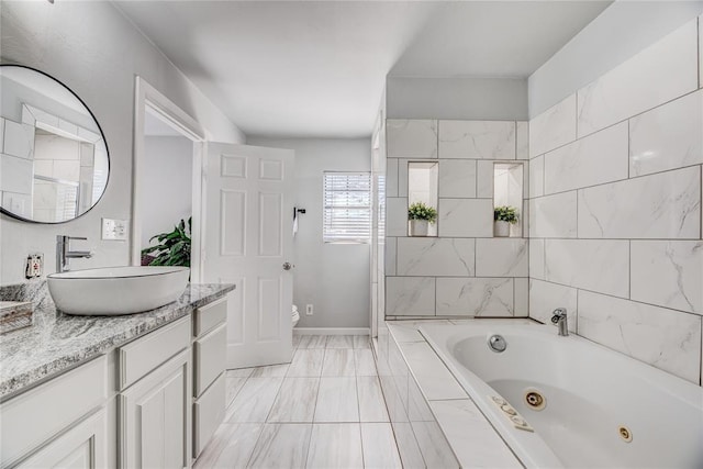 bathroom with vanity, tiled bath, and toilet