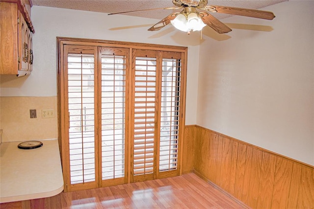 interior space featuring wooden walls, a textured ceiling, and light wood-type flooring