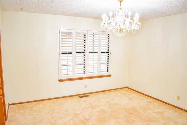 spare room with carpet floors, a chandelier, and a textured ceiling