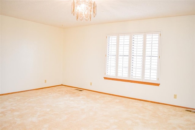 carpeted spare room featuring a notable chandelier and a textured ceiling