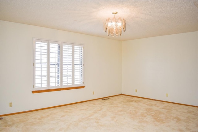 empty room with an inviting chandelier, carpet floors, and a textured ceiling