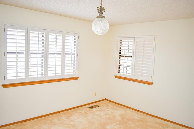 carpeted empty room featuring a textured ceiling