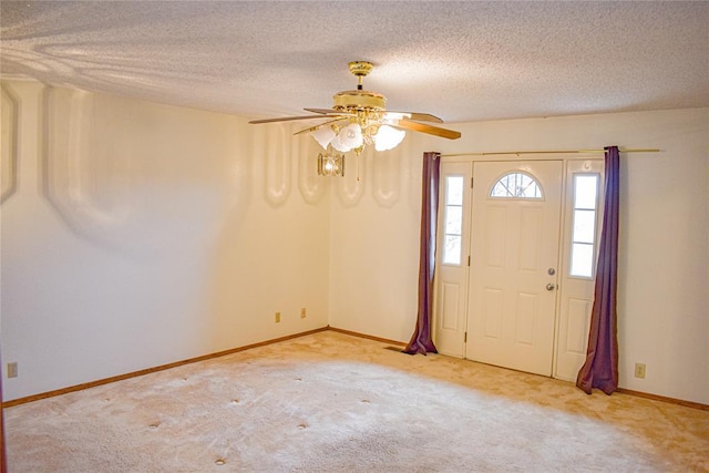 foyer entrance with ceiling fan, light colored carpet, and a textured ceiling