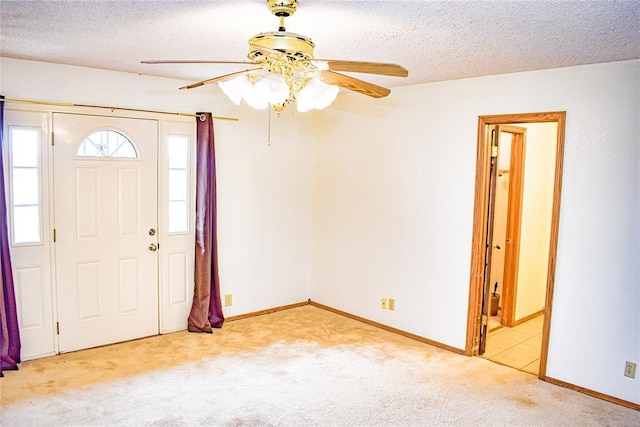 foyer with ceiling fan, light colored carpet, and a textured ceiling