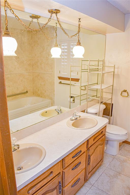 bathroom with vanity, toilet, tile patterned flooring, and a textured ceiling