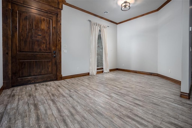 empty room with ornamental molding and light wood-type flooring