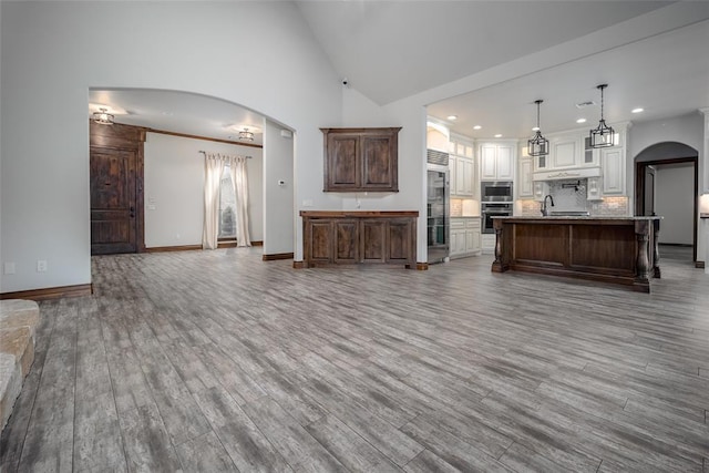 living room with wood-type flooring, sink, and high vaulted ceiling