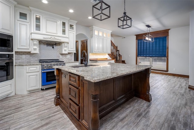 kitchen featuring sink, decorative light fixtures, a center island with sink, appliances with stainless steel finishes, and white cabinets