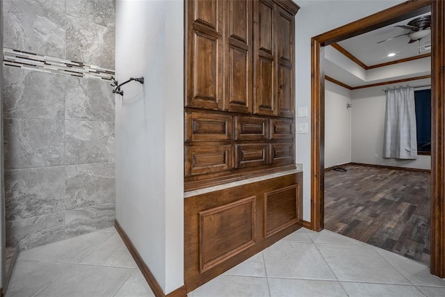 bathroom with tile patterned flooring, crown molding, ceiling fan, and a tray ceiling