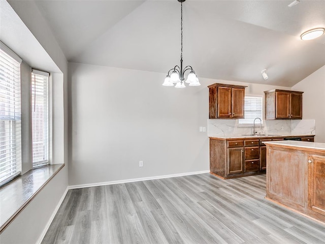 kitchen with pendant lighting, sink, lofted ceiling, and light wood-type flooring