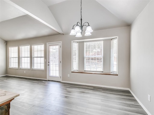 dining room with an inviting chandelier, a healthy amount of sunlight, lofted ceiling, and hardwood / wood-style flooring