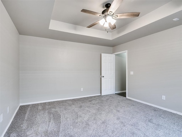 spare room featuring ceiling fan, a tray ceiling, and carpet floors