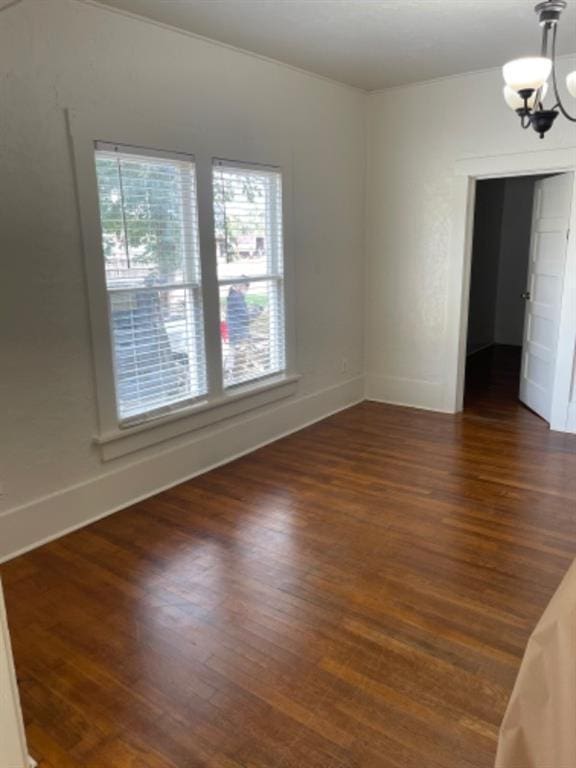 unfurnished room with dark wood-type flooring and an inviting chandelier