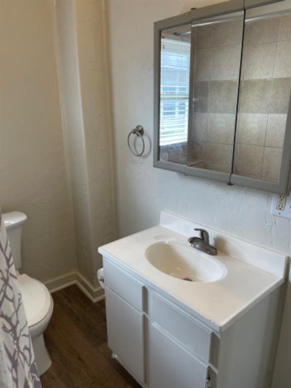 bathroom with hardwood / wood-style flooring, vanity, and toilet