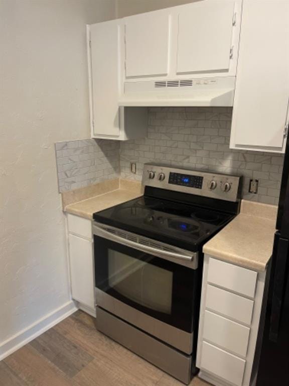 kitchen featuring tasteful backsplash, stainless steel electric range, light hardwood / wood-style floors, and white cabinets