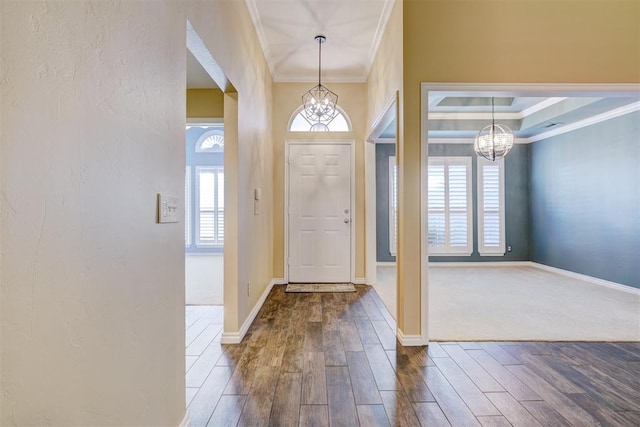 foyer entrance with ornamental molding, hardwood / wood-style floors, and a notable chandelier