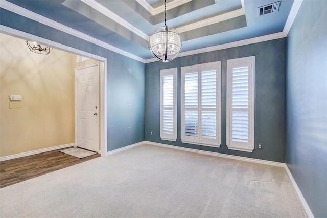 spare room featuring an inviting chandelier, carpet floors, ornamental molding, and a raised ceiling