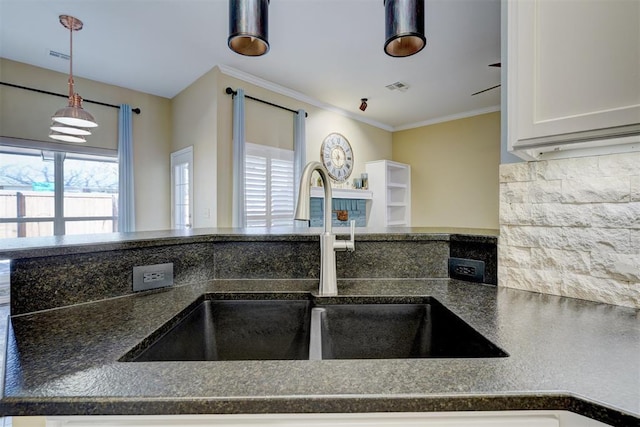 kitchen with pendant lighting, white cabinetry, sink, decorative backsplash, and crown molding