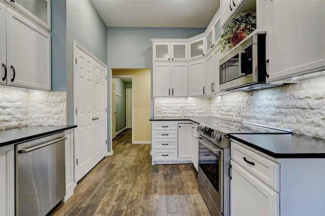 kitchen featuring backsplash, appliances with stainless steel finishes, dark hardwood / wood-style flooring, and white cabinets