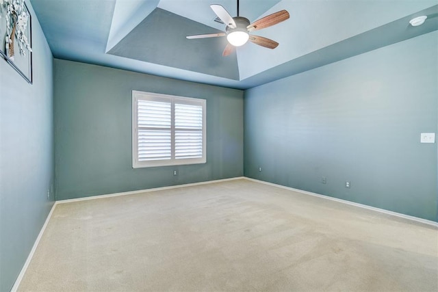 spare room featuring light colored carpet, a raised ceiling, and ceiling fan