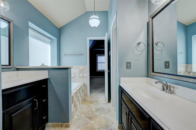 bathroom with tiled tub, vanity, and lofted ceiling