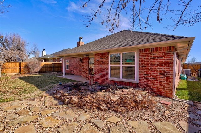 rear view of house featuring a patio, central AC unit, and a lawn