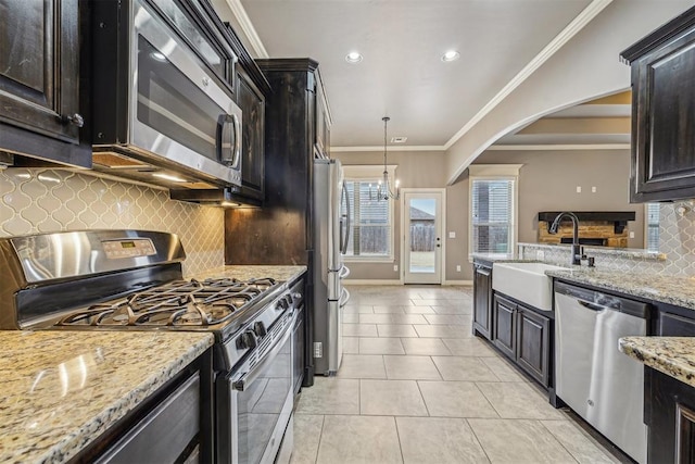 kitchen with sink, crown molding, light tile patterned floors, stainless steel appliances, and decorative light fixtures