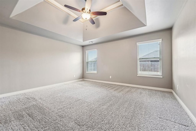 unfurnished room featuring a tray ceiling, ceiling fan, and carpet flooring