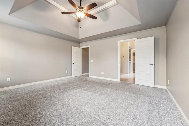 unfurnished bedroom with a raised ceiling, light colored carpet, and ceiling fan