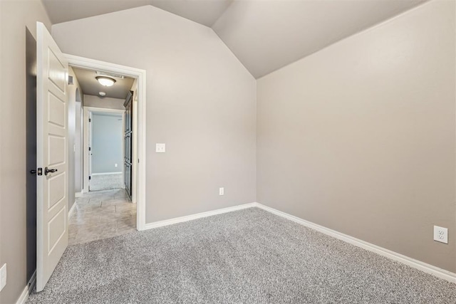 carpeted empty room featuring vaulted ceiling