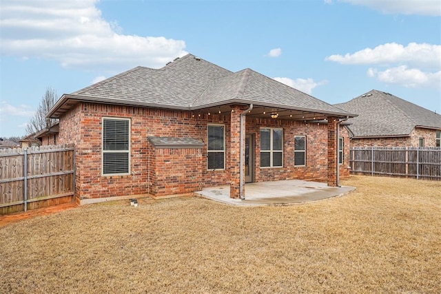 rear view of house featuring a lawn and a patio