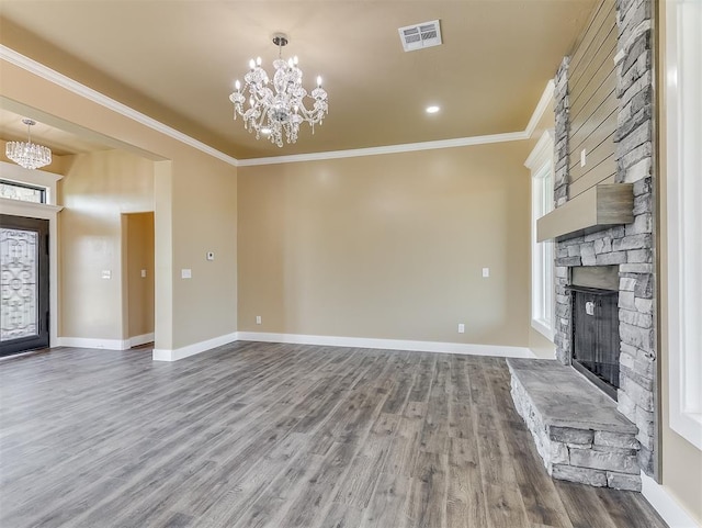 unfurnished living room with a fireplace, hardwood / wood-style flooring, a notable chandelier, crown molding, and a healthy amount of sunlight