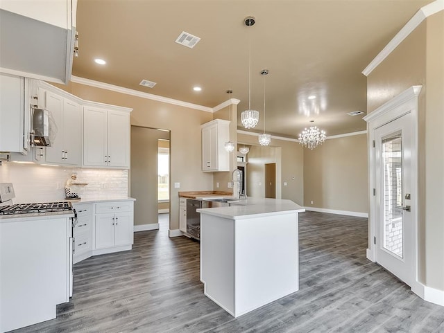 kitchen with decorative light fixtures, ornamental molding, white range with gas stovetop, and white cabinets