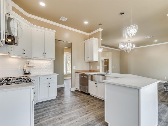 kitchen featuring sink, hanging light fixtures, stainless steel dishwasher, light hardwood / wood-style floors, and white cabinets