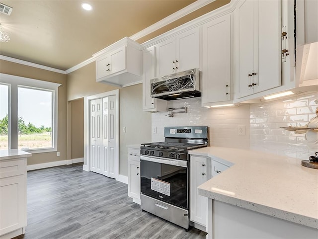 kitchen featuring stainless steel gas stove, ventilation hood, ornamental molding, white cabinets, and decorative backsplash