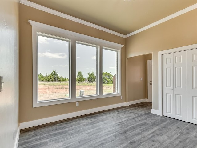 unfurnished bedroom featuring crown molding, a closet, and light wood-type flooring